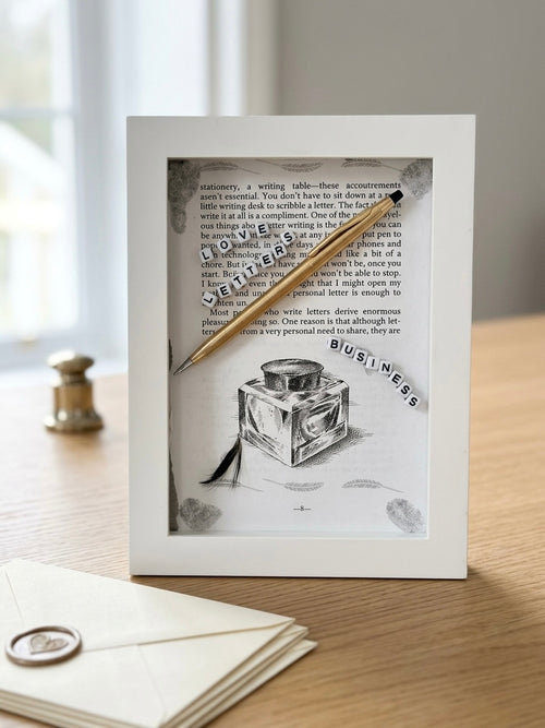 3D shadowbox artwork in a white frame featuring a book page about letter writing, a gold pen, an inkwell illustration, and the words "Lovers Letters" and "Business" spelled in letter beads.